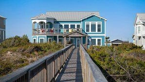 A two-story house with a balcony and a wooden deck leading to the entrance.