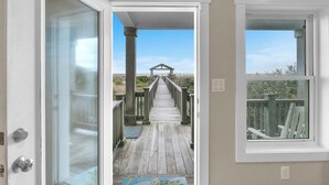 A wooden deck leading to a covered area with a view of the landscape.