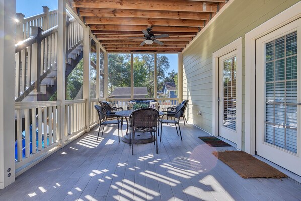 Enjoy dining or meeting in this covered outdoor space with a ceiling fan, stairs, and a table with chairs.
