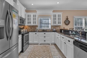 Kitchen features a large island with a sink and a dishwasher, along with a window and a clock.