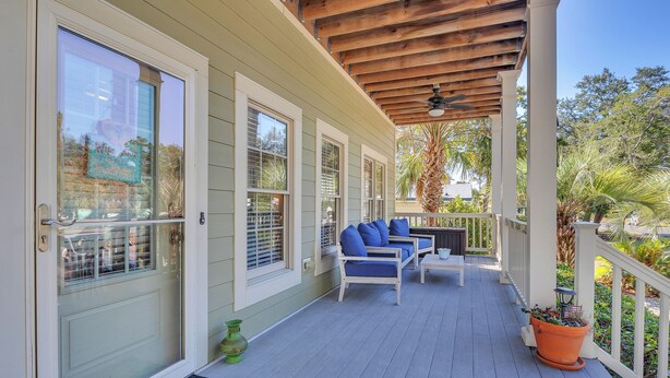Eine überdachte Veranda mit Holzboden, eine Sitzecke mit blauen Kissen und einem Blumentopf.
