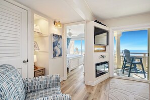 Une chambre avec un lit, une chaise, une cheminée, une télévision et un balcon avec vue.