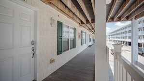A corridor with white doors, numbered 4101, leading to a building with a wooden ceiling and a balcony. - OW 4101: Serene Condo with Community Pool, Elevator (Oak Island)