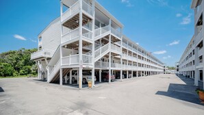 A multi-story parking garage with white railings and a clear blue sky. - OW 4101: Serene Condo with Community Pool, Elevator (Oak Island)
