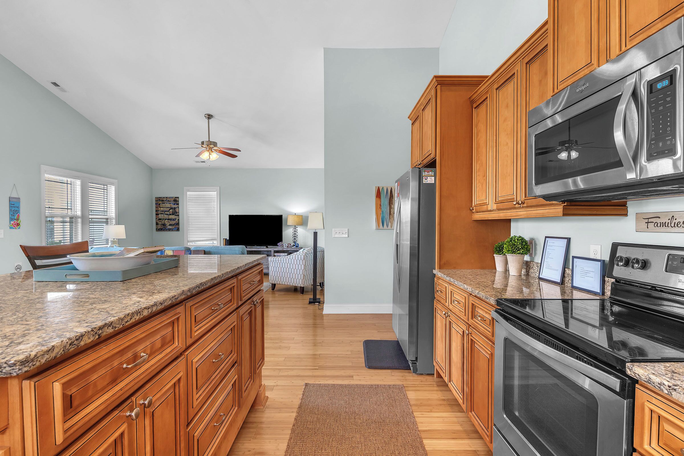 A kitchen with wooden cabinets, a granite countertop, a stainless steel refrigerator, a microwave, and an oven.