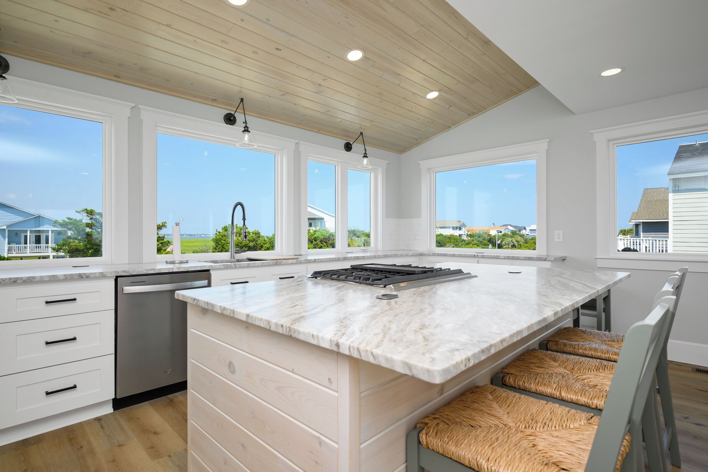 A modern kitchen with a large island, white cabinetry, and a view of the neighborhood.