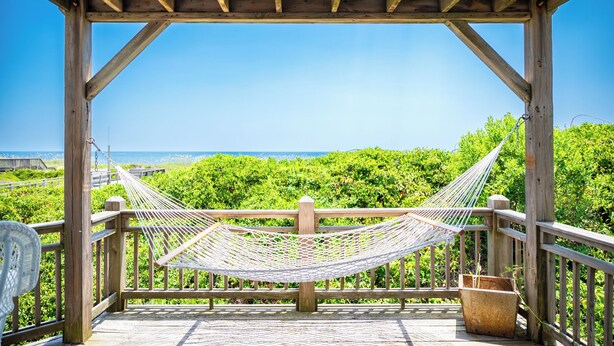 A wooden deck with a hammock and a view of the ocean. - Beach Buzz: Oceanfront with Expansive Beach and Sound Side Decks (Caswell Beach)