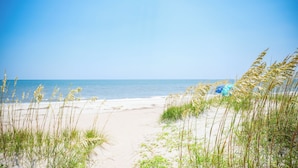 A beach path leading to the ocean with sand and grass on either side. - Beach Buzz: Oceanfront with Expansive Beach and Sound Side Decks (Caswell Beach)