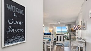 Ein Zimmer mit Meerblick, ein Schild mit der Aufschrift 'Welcome to Ocean Breeze' und ein Essbereich mit weißer Möbel.