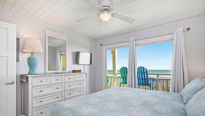 Ein Schlafzimmer mit Bett, Schminktisch, Lampe, Fernseher und einem Balkon mit Stühlen.