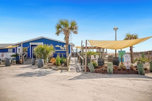 Un bâtiment sur lequel on peut lire l’inscription « Island Way Restaurant & Bar », et qui dispose d’un espace extérieur abrité avec des tables et des chaises.