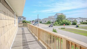 Un balcón de madera con vistas a una calle residencial, con casas y coches aparcados.