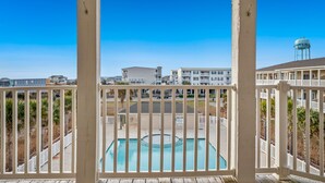 Una terrassa de fusta amb vista a una piscina i els edificis circumdants.