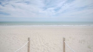 Una playa con valla de madera y barrera de cuerda.