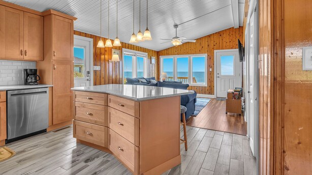 Una cocina moderna con armarios de madera, lavavajillas de acero inoxidable y luces colgantes.