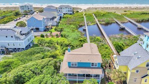 Une zone résidentielle côtière comprenant plusieurs maisons, un quai et une plage en arrière-plan.