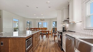 Une cuisine spacieuse dotée de meubles en bois, d’un plan de travail en granit et d’un coin repas avec des chaises en bois.
