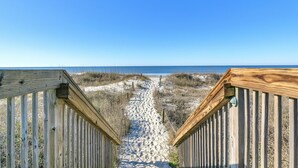 A wooden boardwalk leading to a beach with clear skies. - Balcony At The Beach: Oceanfront Condo with Community Pool (Caswell Beach)