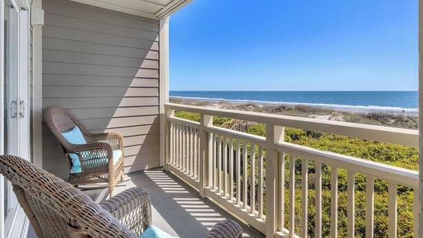 A balcony with wicker furniture and a view of the beach. - Balcony At The Beach: Oceanfront Condo with Community Pool (Caswell Beach)
