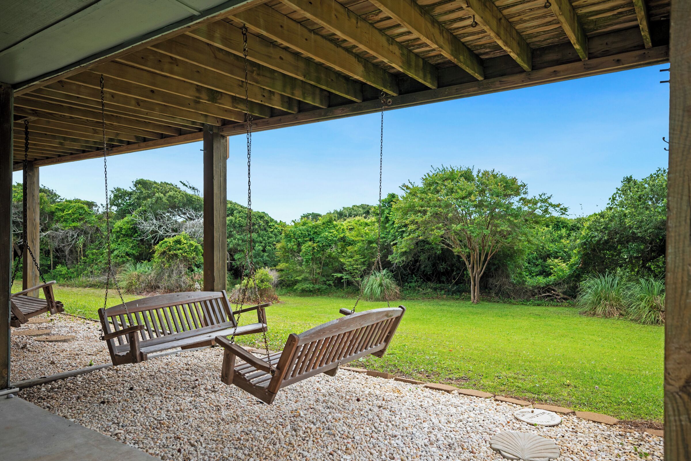 A covered outdoor seating area with benches and a gravel path.