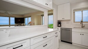 Een moderne keuken met witte kasten, een vaatwasser en een raam met uitzicht op een prachtig panorama.
