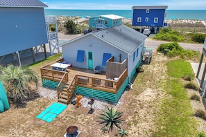 Une maison située en bord de mer, dotée d’une terrasse, d’un petit espace salon extérieur et offrant une vue sur l’océan.