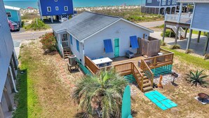 A beachfront house with a deck, a small patio, and a view of the ocean.