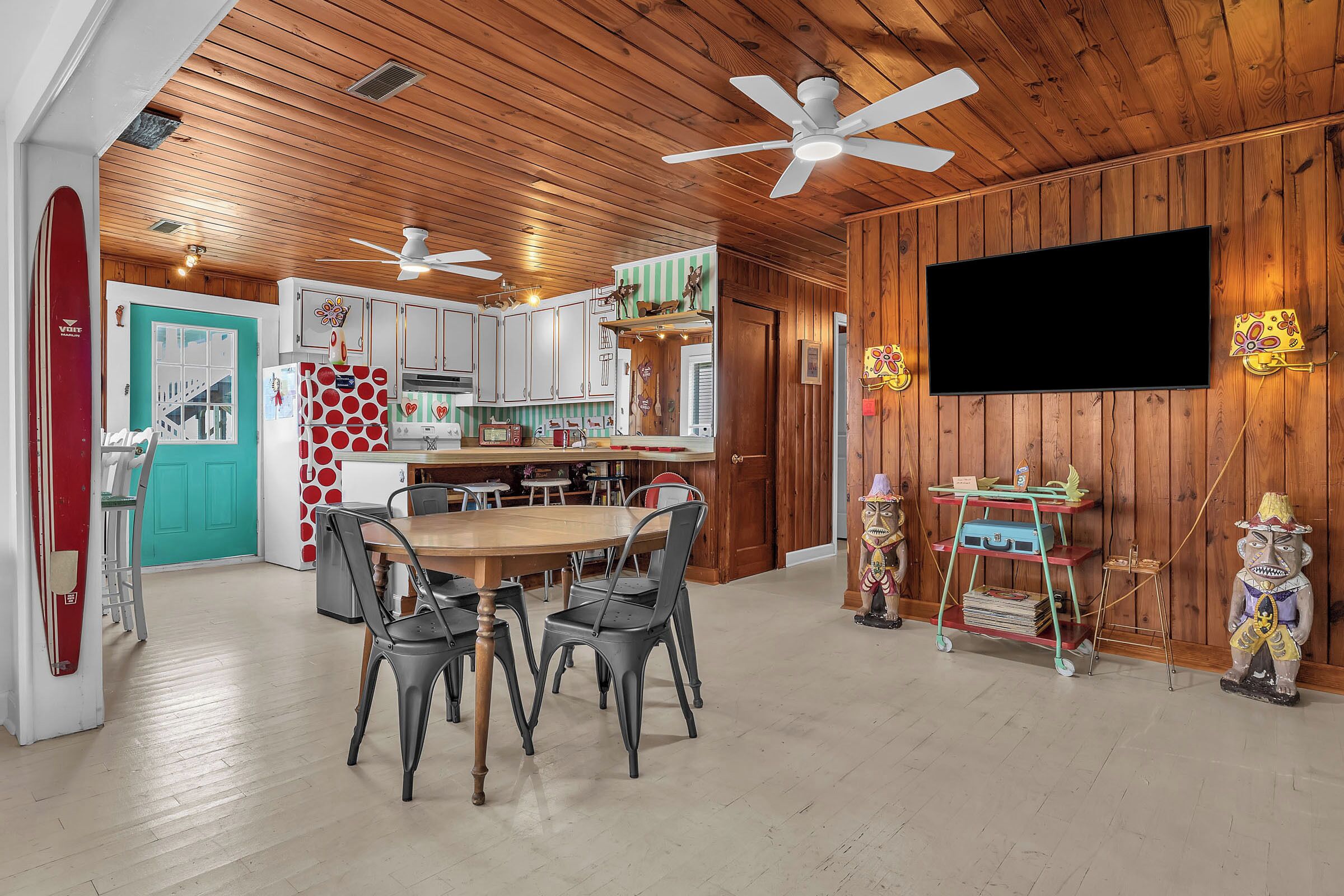 A wooden interior with a dining area, kitchen, and a TV mounted on the wall.