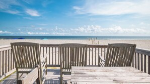 Une terrasse en bois avec quatre chaises donnant sur une plage.