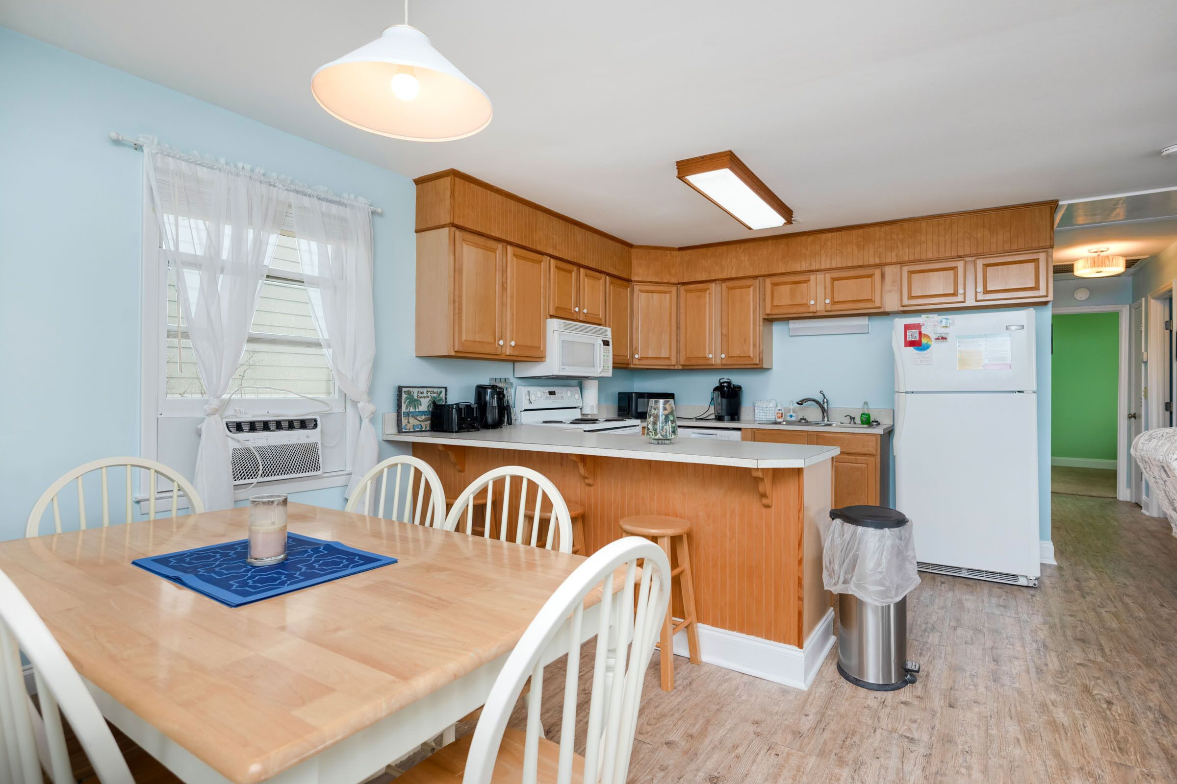 A compact kitchen with wooden cabinets, a white refrigerator, a microwave, and a coffee maker.