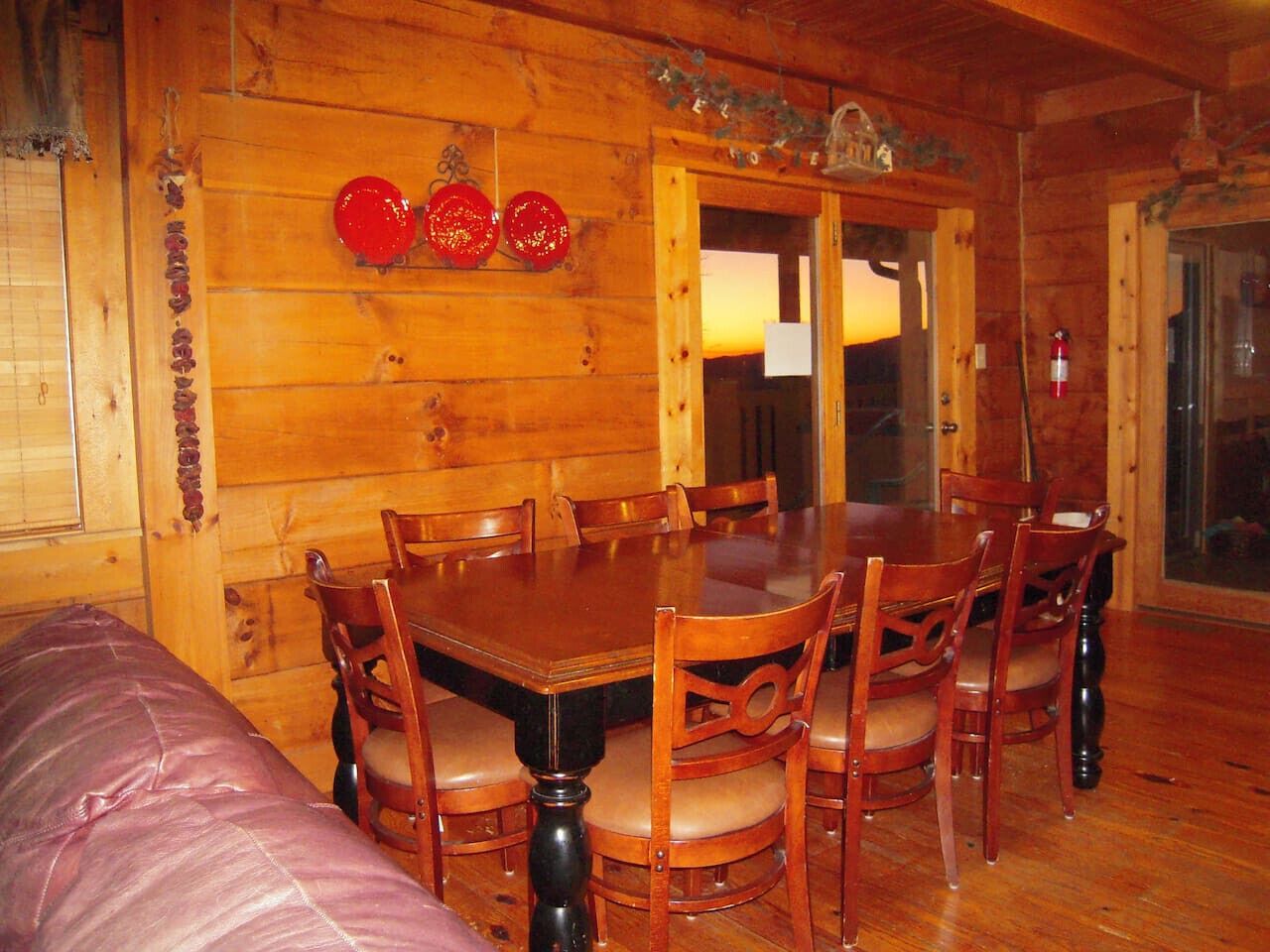 A wooden dining room with a large table and chairs, a wooden bench, and a door with a glass panel.