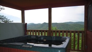Un jacuzzi en una cabaña de madera con vistas a una cordillera boscosa.