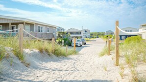 Una propiedad frente a la playa con varias casas, un camino de arena y una valla de madera.