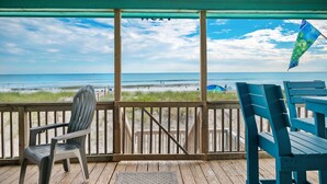 A wooden deck with a view of the beach and ocean. - A Pirate's Paradise: Oceanfront Home with Covered Porch and Porch Swing (Oak Island)