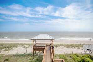 Une vue sur la plage avec une structure en bois et une promenade en planches menant à la plage.