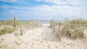 A sandy beach path leading to the ocean with a sign reading 'The Dunes.'
