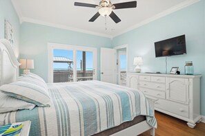 Une chambre à coucher comprenant un lit, une commode, un téléviseur et un ventilateur de plafond.