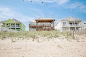 A beachfront property with a wooden structure, a green building, and a white building. - Island Retreat: Beautiful Oceanfront Home w/Gazebo in West Beach (Oak Island)