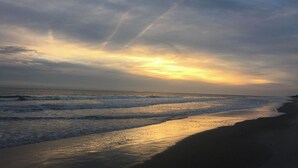 Ein Strand mit Wellen und einem Sonnenuntergang.