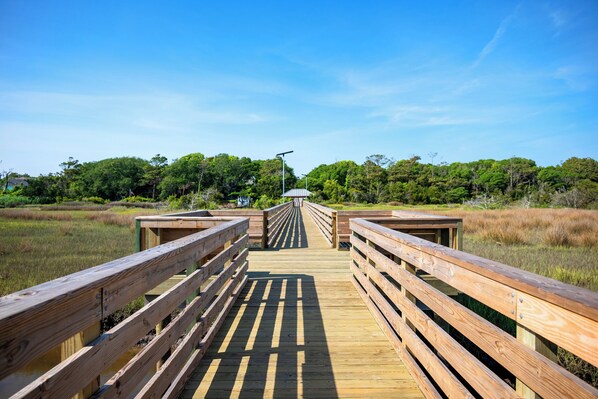 A wooden boardwalk leading to a gazebo in a natural setting.