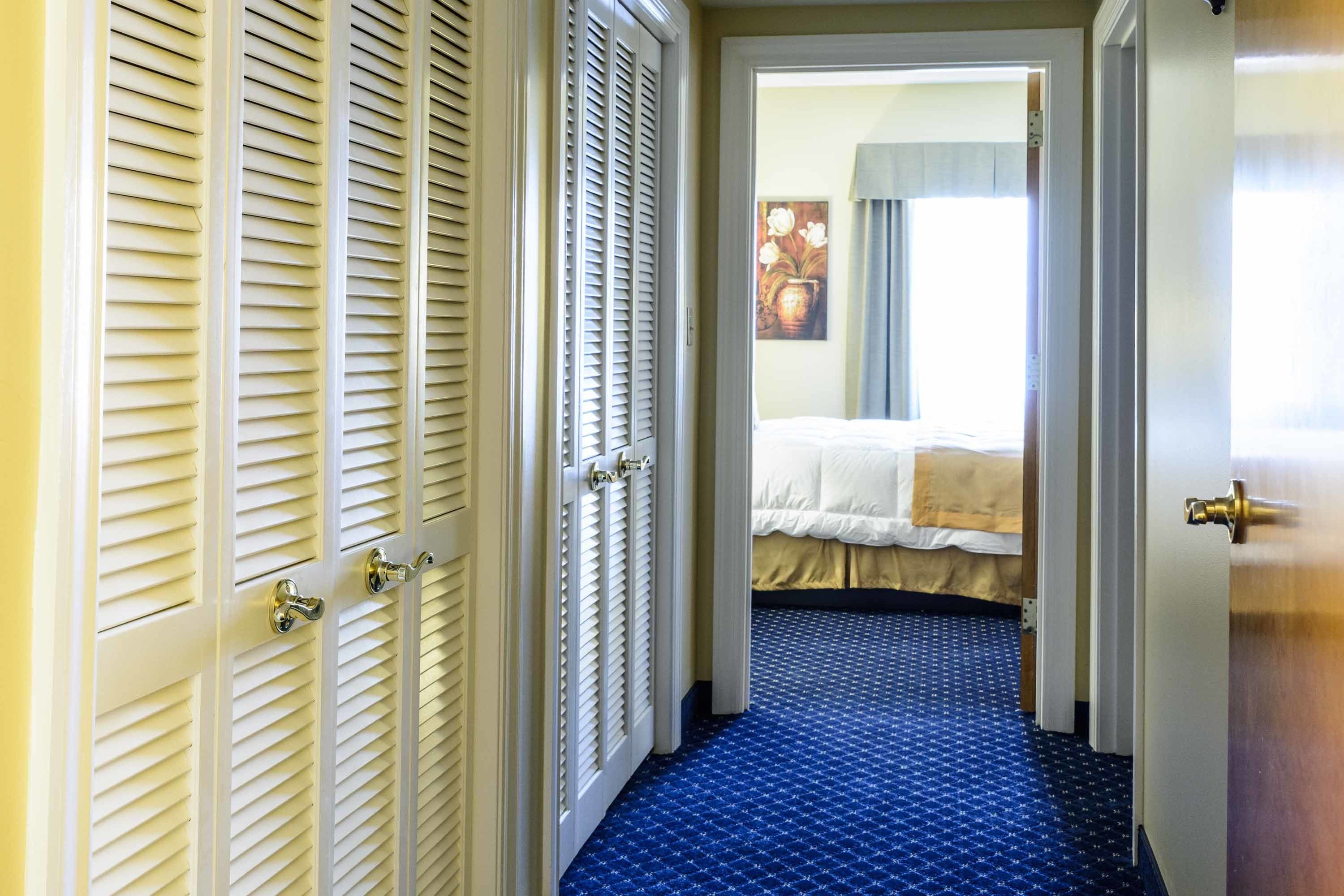 Una habitación de hotel con una cama, una puerta con manija y una alfombra estampada.