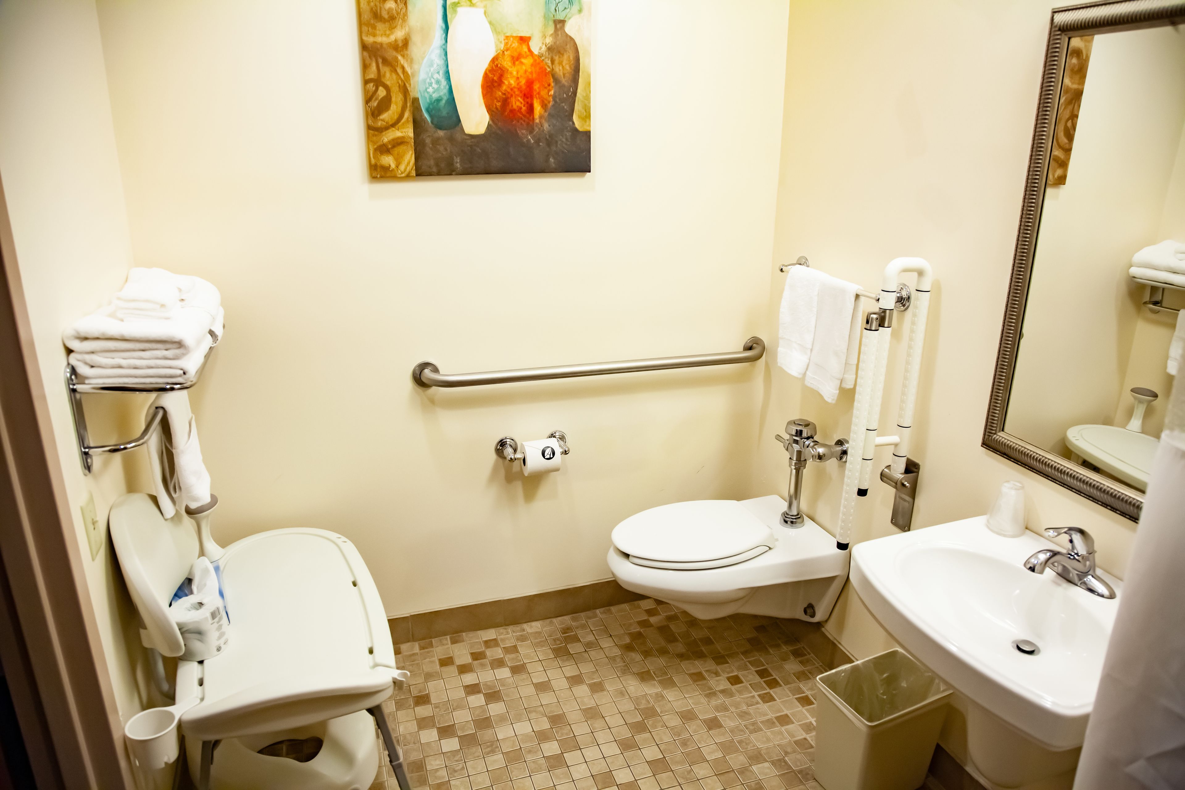 Un baño con inodoro accesible para sillas de ruedas, un lavabo y un espejo.