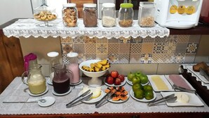 A buffet table with various food items and beverages, including fruits, breads, and drinks. - Pousada Cores do Mar (Paraty)