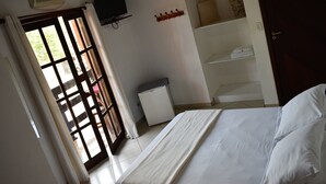 A bedroom with a bed, a television, a small refrigerator, and a door leading outside. - Pousada Cores do Mar (Paraty)