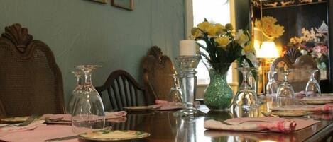 Une table à manger dressée avec des assiettes, des couverts et un vase rempli de fleurs jaunes.