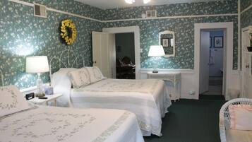 A room with two beds, a desk, a chair, a mirror, and a door leading to another room.