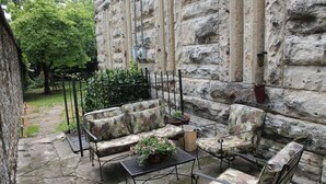 An outdoor seating area with a stone wall backdrop, a metal table, and patterned cushions.
