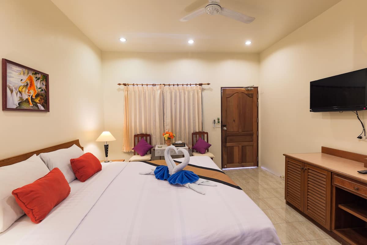 Una habitación de hotel con una cama, televisión, escritorio y puerta.