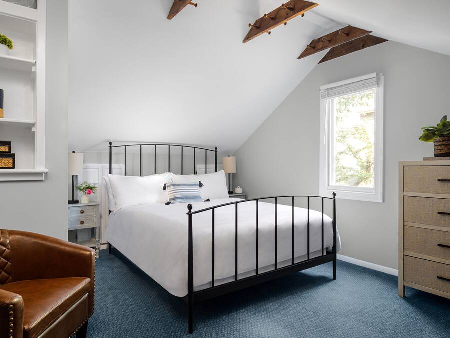 A bedroom with a bed, a chair, a dresser, and a window.
