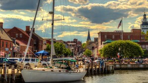 A sailboat docked at a waterfront with buildings in the background.